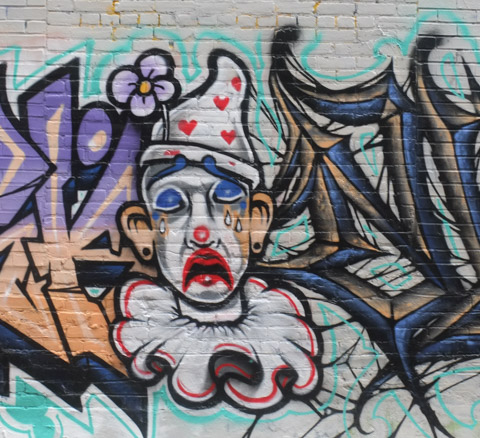 part of a mural, a clown with large white collar, white hat with red hearts on it, and a lot of white face make up is crying big tears, flower in his hat, big red mouth, 