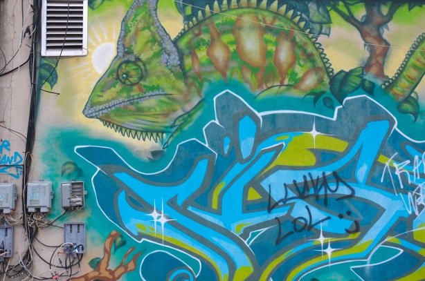 large green iguana in a mural, looks unhappy