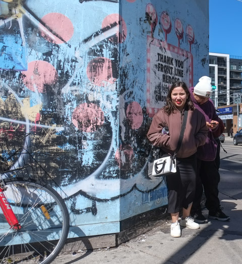 two people standing beside defaced mural in support of front line workers, dundas west and bloor