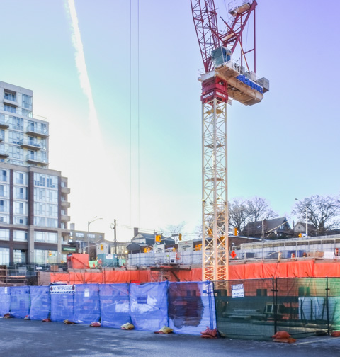 large crane and orange barriers along the edge of a construction site on bloor near keele station