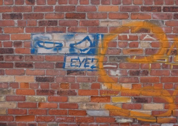 graffiti on a brick wall in an alley, blue eyes with text eyez