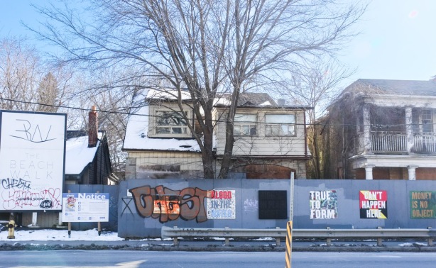 hoardings with signs on them, blue painted plywood, snow on roof of abandoned house, 