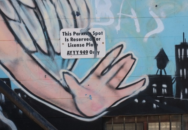 a hand with open palm in a mural beside a small sign that says parking reserved