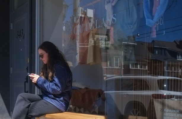 a woman sits on a bench in front of a store window