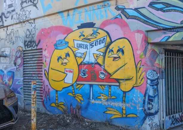 uber 5000 mural with three yellow birdies sitting around a red table. One is reading a newspaper